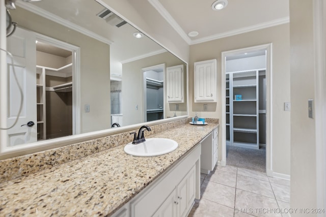 bathroom with a spacious closet, tile patterned flooring, baseboards, ornamental molding, and vanity