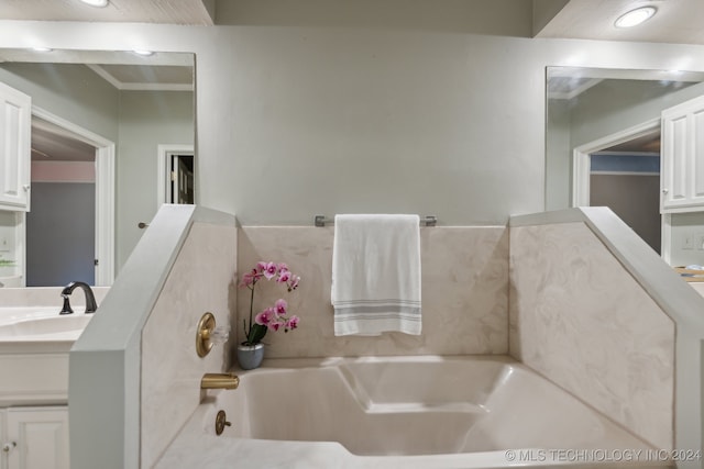 bathroom featuring a garden tub, vanity, and crown molding