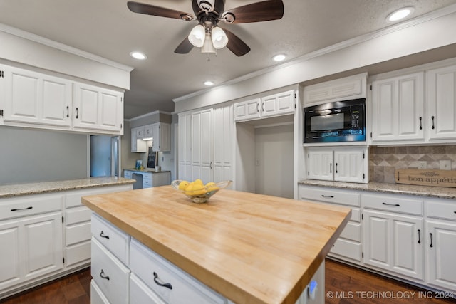 kitchen featuring wooden counters, black microwave, a kitchen island, dark hardwood / wood-style floors, and white cabinetry