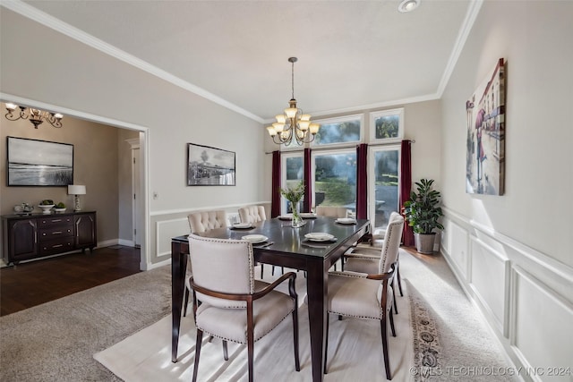 dining area with crown molding, a chandelier, a wainscoted wall, carpet flooring, and a decorative wall