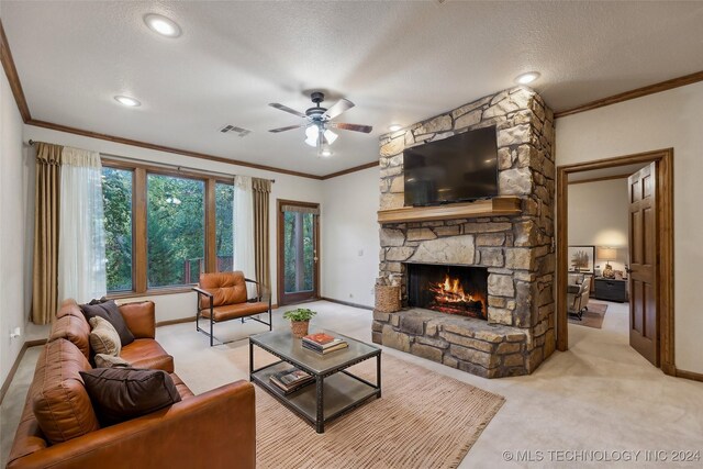 carpeted living room featuring ceiling fan, a stone fireplace, crown molding, and a textured ceiling