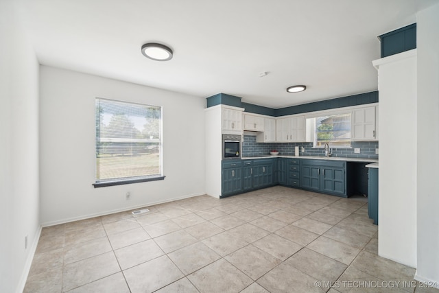 kitchen with gray cabinetry, white cabinetry, light tile patterned flooring, backsplash, and oven