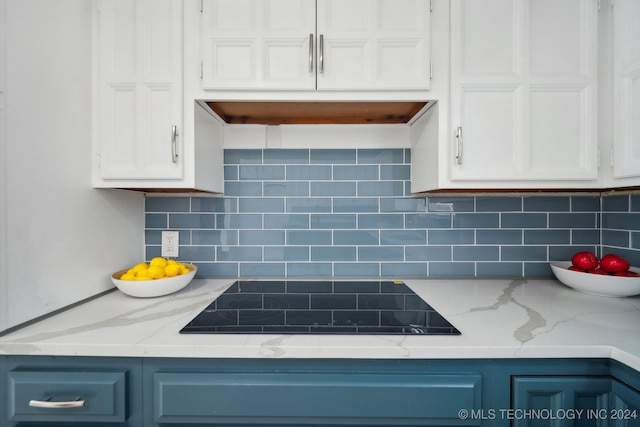 kitchen featuring blue cabinetry, light stone counters, tasteful backsplash, and black electric cooktop