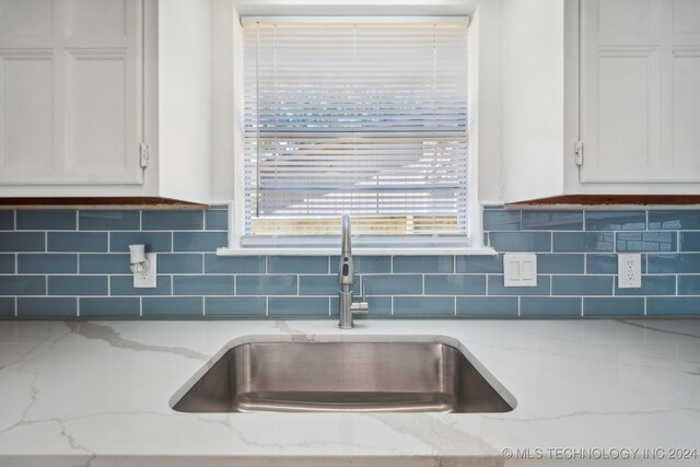 kitchen featuring light stone countertops, sink, and tasteful backsplash