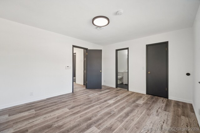 unfurnished bedroom featuring connected bathroom and light hardwood / wood-style floors