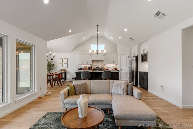 living room featuring a notable chandelier, lofted ceiling, and light hardwood / wood-style flooring