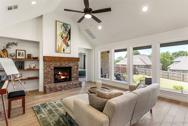 living room with high vaulted ceiling, a brick fireplace, light hardwood / wood-style floors, and ceiling fan