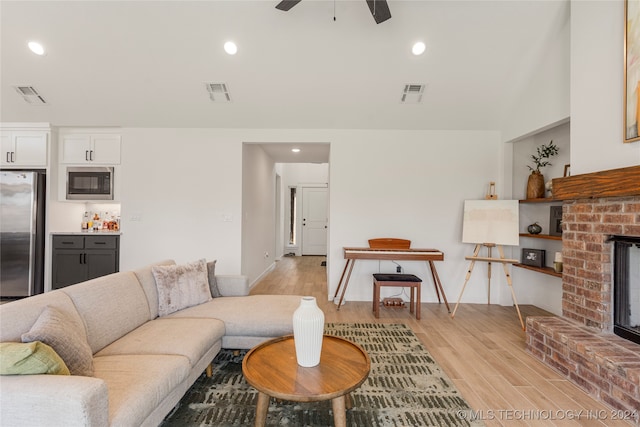 living room featuring light hardwood / wood-style floors, ceiling fan, and a fireplace