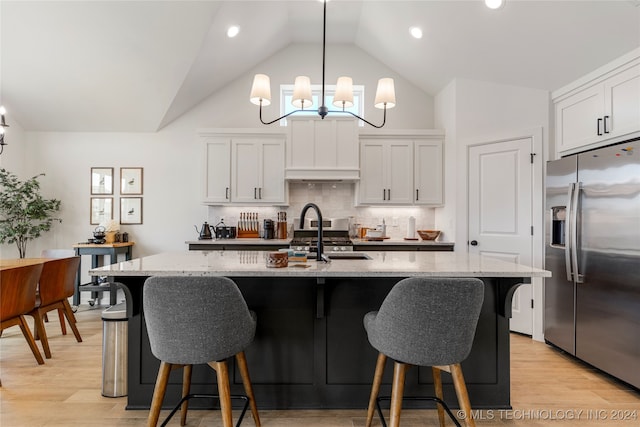 kitchen with an inviting chandelier, stainless steel appliances, a kitchen island with sink, and white cabinetry