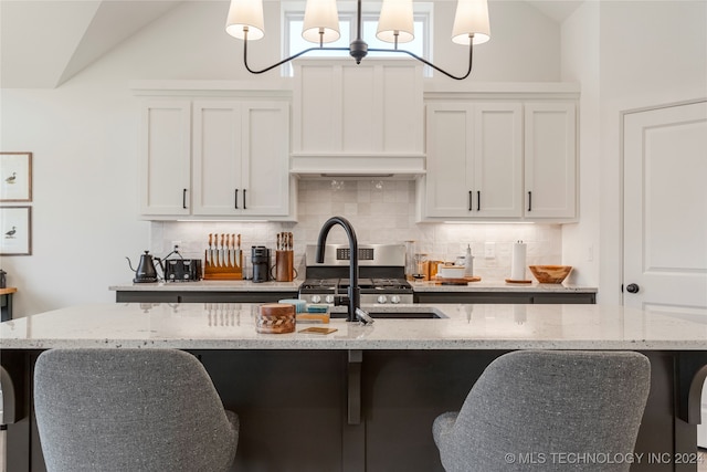 kitchen with white cabinets, a kitchen island with sink, and hanging light fixtures