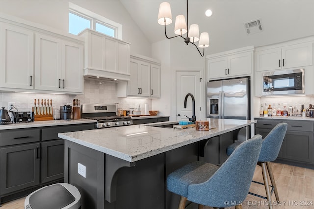 kitchen with an island with sink, white cabinetry, appliances with stainless steel finishes, and pendant lighting