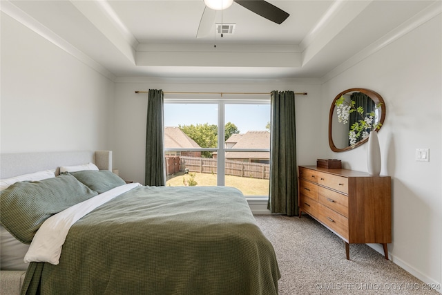 bedroom with ornamental molding, a tray ceiling, ceiling fan, and light colored carpet