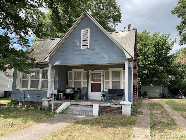 bungalow-style home with a front lawn, central air condition unit, and covered porch