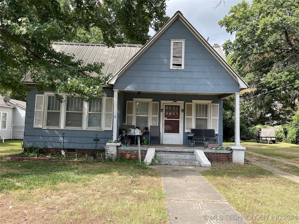 bungalow-style home with a front yard and covered porch