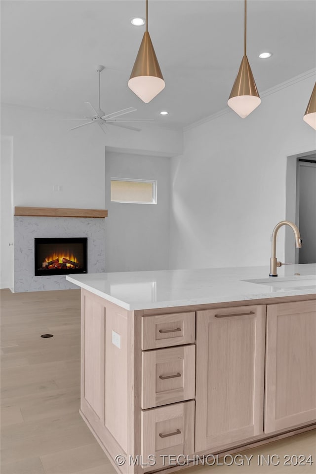 kitchen with ceiling fan, light brown cabinets, hanging light fixtures, and crown molding