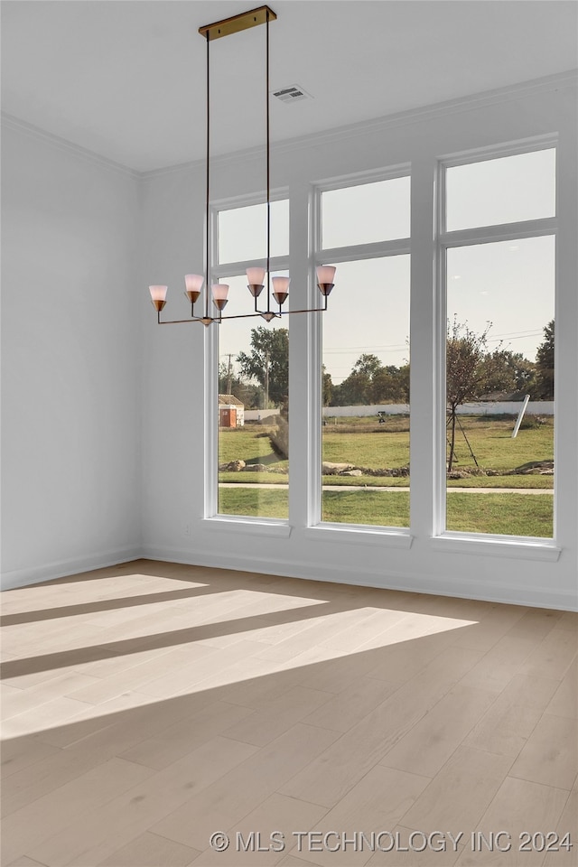 unfurnished dining area featuring ornamental molding, a chandelier, light hardwood / wood-style floors, and a healthy amount of sunlight