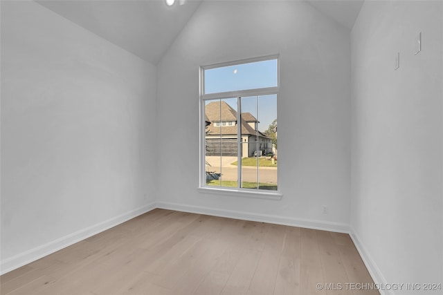 unfurnished room featuring lofted ceiling and light hardwood / wood-style floors