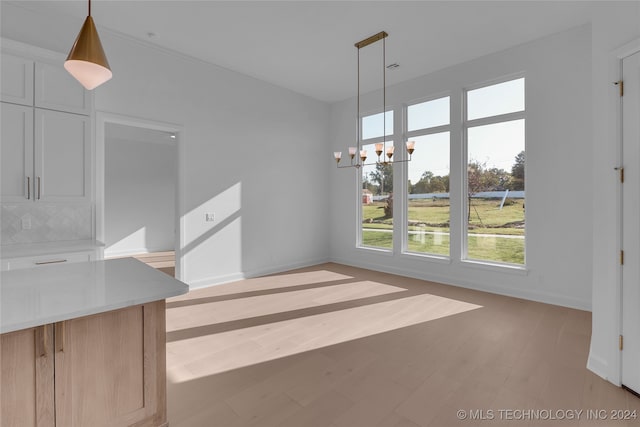 unfurnished dining area featuring an inviting chandelier and light wood-type flooring