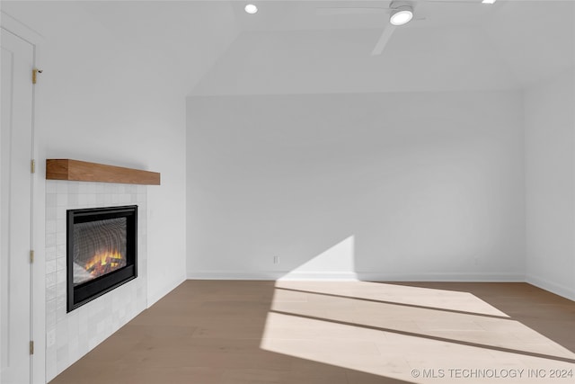 unfurnished living room featuring a tiled fireplace, ceiling fan, vaulted ceiling, and hardwood / wood-style flooring