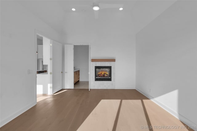 unfurnished living room featuring ceiling fan, light hardwood / wood-style flooring, and a tiled fireplace