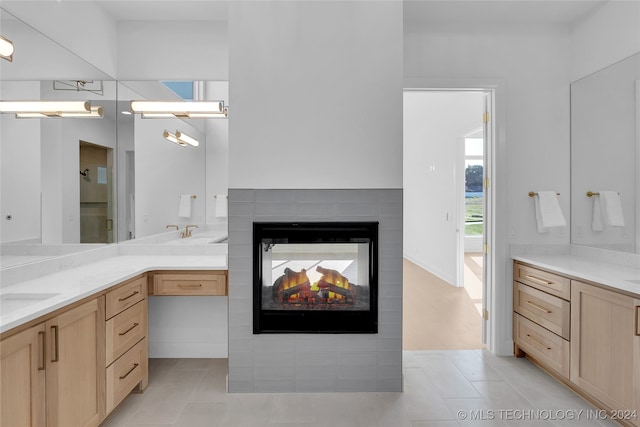 bathroom with walk in shower, a multi sided fireplace, vanity, and tile patterned flooring