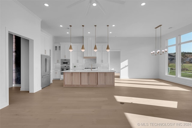 kitchen featuring white cabinets, hanging light fixtures, a large island, stainless steel appliances, and decorative backsplash