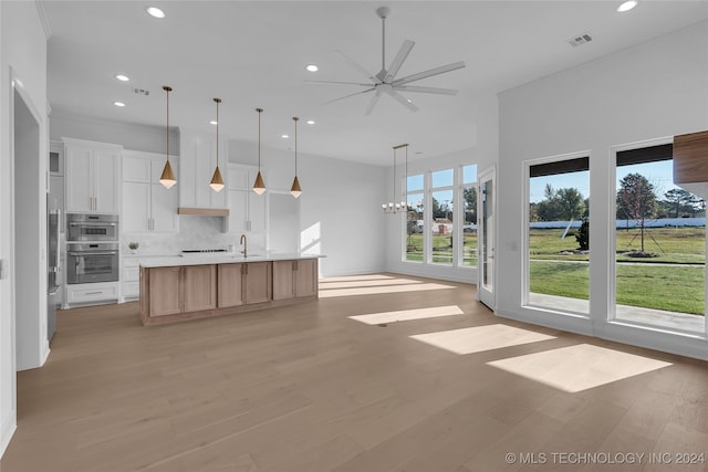 kitchen featuring a large island, white cabinetry, decorative backsplash, light hardwood / wood-style flooring, and crown molding