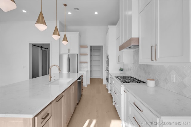 kitchen with appliances with stainless steel finishes, pendant lighting, an island with sink, and white cabinets