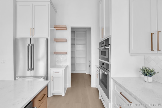 kitchen with light stone countertops, high quality fridge, tasteful backsplash, and white cabinetry