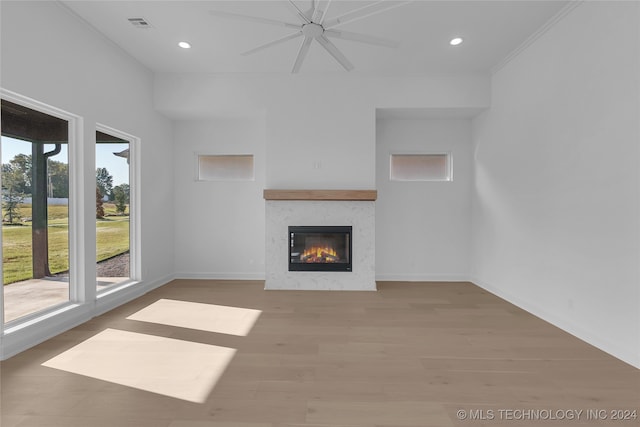 unfurnished living room featuring a wealth of natural light, light hardwood / wood-style floors, a premium fireplace, and ceiling fan