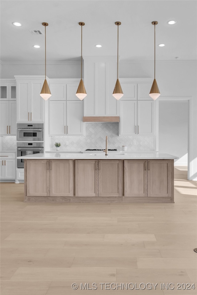 kitchen with white cabinetry, stainless steel double oven, and a large island with sink