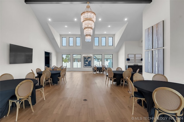 living room featuring light hardwood / wood-style flooring, a high ceiling, and a chandelier