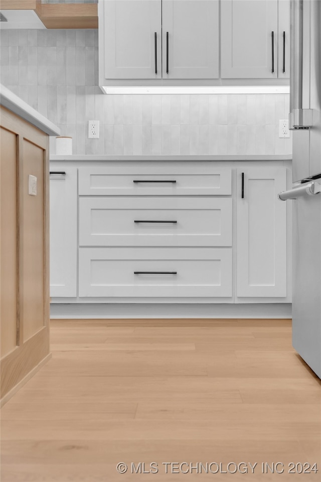 kitchen featuring white cabinets, backsplash, light hardwood / wood-style floors, and stainless steel fridge