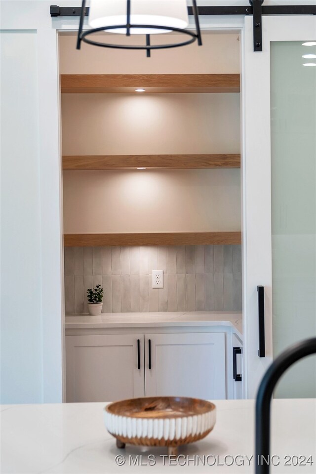 interior space featuring backsplash, white cabinetry, and a barn door