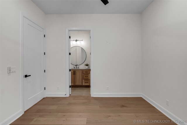 unfurnished bedroom featuring sink, ensuite bath, and light hardwood / wood-style floors