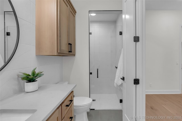 bathroom featuring toilet, vanity, hardwood / wood-style floors, and a shower with door