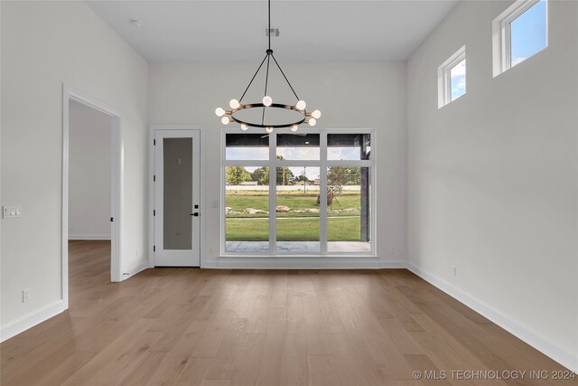 unfurnished dining area featuring light wood-type flooring and a notable chandelier