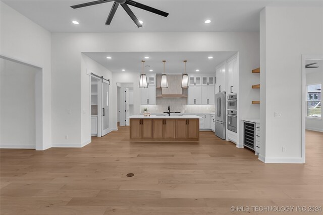 kitchen featuring white cabinetry, a barn door, ceiling fan, decorative light fixtures, and a large island