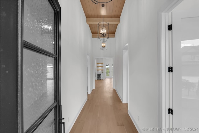 corridor with wooden ceiling, light wood-type flooring, beam ceiling, and an inviting chandelier