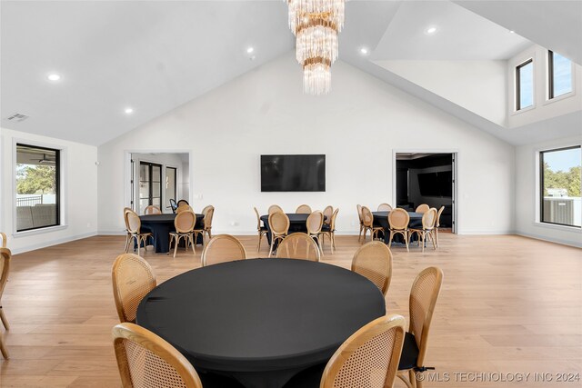 dining room with a notable chandelier, light hardwood / wood-style flooring, and high vaulted ceiling