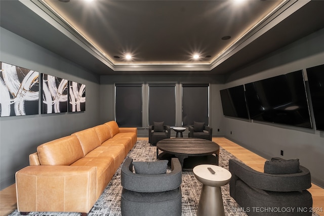 home theater room with wood-type flooring and a tray ceiling