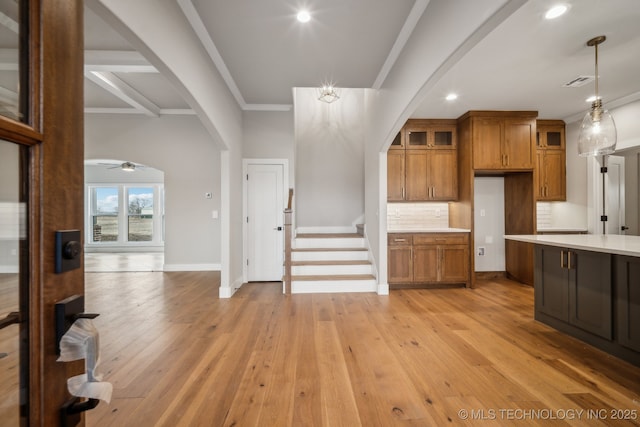 kitchen featuring tasteful backsplash, crown molding, light hardwood / wood-style floors, and decorative light fixtures