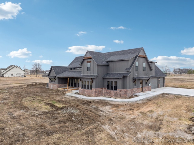 exterior space with concrete driveway, brick siding, and roof with shingles