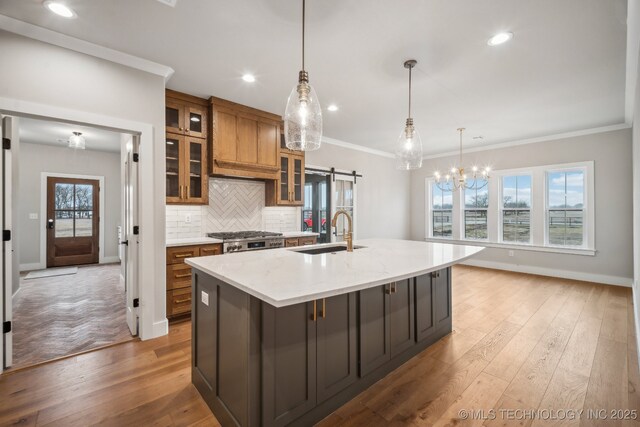 kitchen featuring sink, hanging light fixtures, a barn door, light stone countertops, and a spacious island