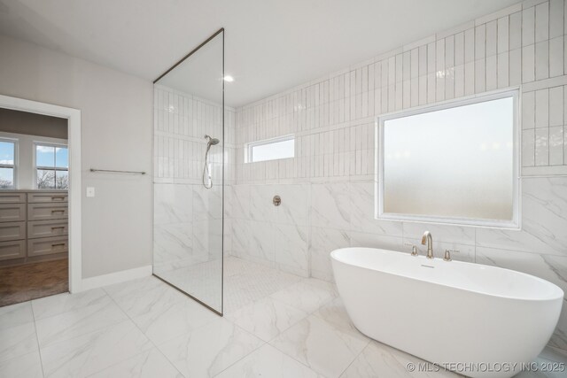 bathroom with tile walls and shower with separate bathtub