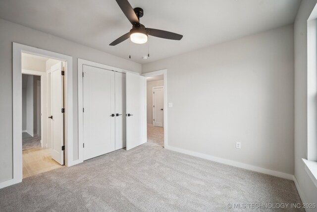 unfurnished bedroom featuring connected bathroom, light colored carpet, a closet, and ceiling fan