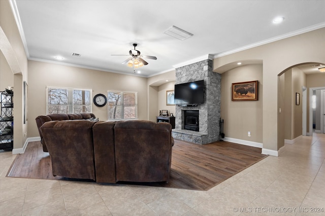 living room featuring light hardwood / wood-style flooring, ceiling fan, a fireplace, and ornamental molding