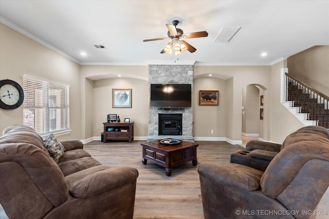 living room with light wood-type flooring, a fireplace, ornamental molding, and ceiling fan