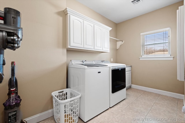 laundry room featuring washer and clothes dryer, cabinets, and light tile patterned flooring