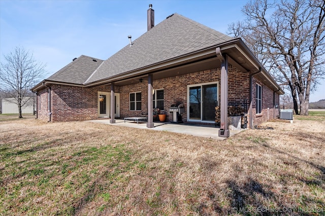 rear view of property with a yard, central air condition unit, and a patio area